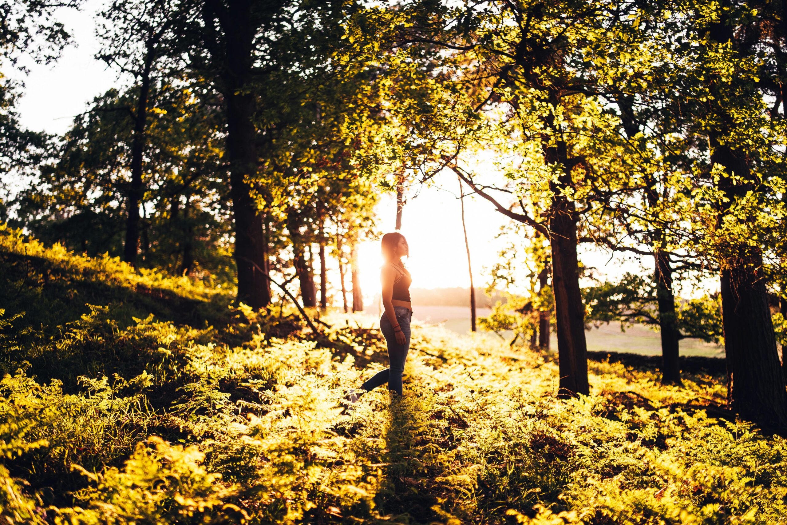 Woman standing peacefully in sunlit forest