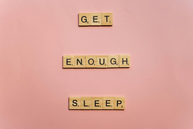 Scrabble tiles on a pink background spelling out 'Get Enough Sleep'. Ideal for wellness and lifestyle themes.